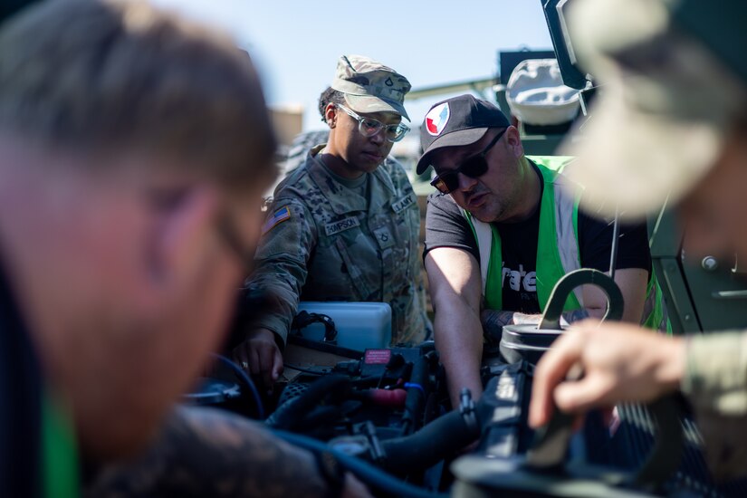 Pfc. Ayana Thompson, assigned to the 43rd Multi-Role Bridge Company, 20th Engineer Battalion, and Dominique Maes, a host nation Department of Defense civilian employee from Army Field Support Battalion-Benelux conduct preventive maintenance checks and services on a vehicle from the Army Prepositioned Stock-2 (APS-2) program at Drawsko Combat Training Center, Poland, May 1, 2024. Maes traveled from the APS-2 worksite in Zutendaal, Belgium, and traveled to Poland to issue equipment for DEFENDER 24. (U.S. Army photo by Staff Sgt. Rene Rosas)