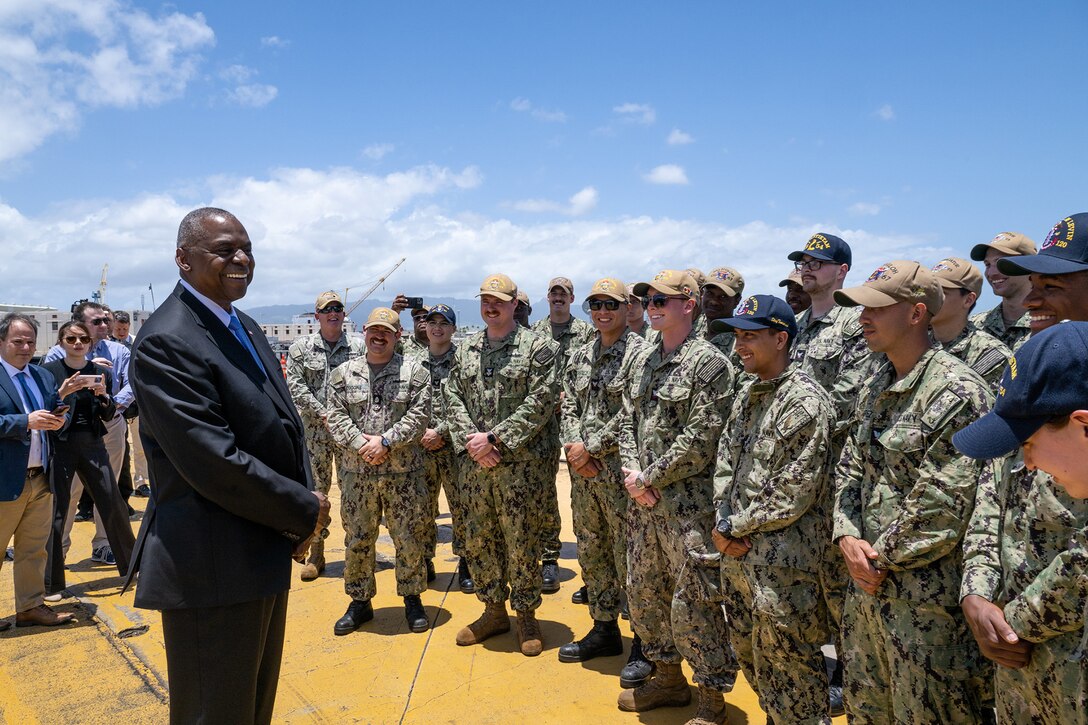 Secretary of Defense Lloyd J. Austin III speaks to a group of service members outdoors.
