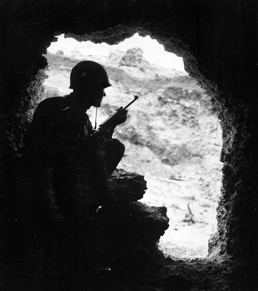 American Marine uses an M1 Carbine to snipe at Japanese positions from an Okinawan cave