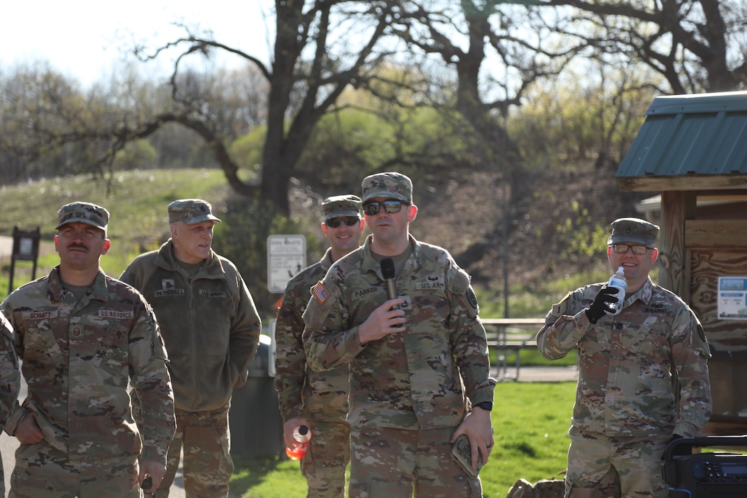 Sgt. 1st Class Levi Parker (center) speaks to the crowd of over 90 Wisconsin National Guard service members during the safety brief of the Norwegian foot march event hosted by the 54th Civil Support Team. The Norwegian foot march challenges participants to complete 30 kilometers (18.6 miles) while carrying at least 24 pounds in a rucksack on their back. (U.S. National Guard photo by Staff Sgt. Amber Peck)