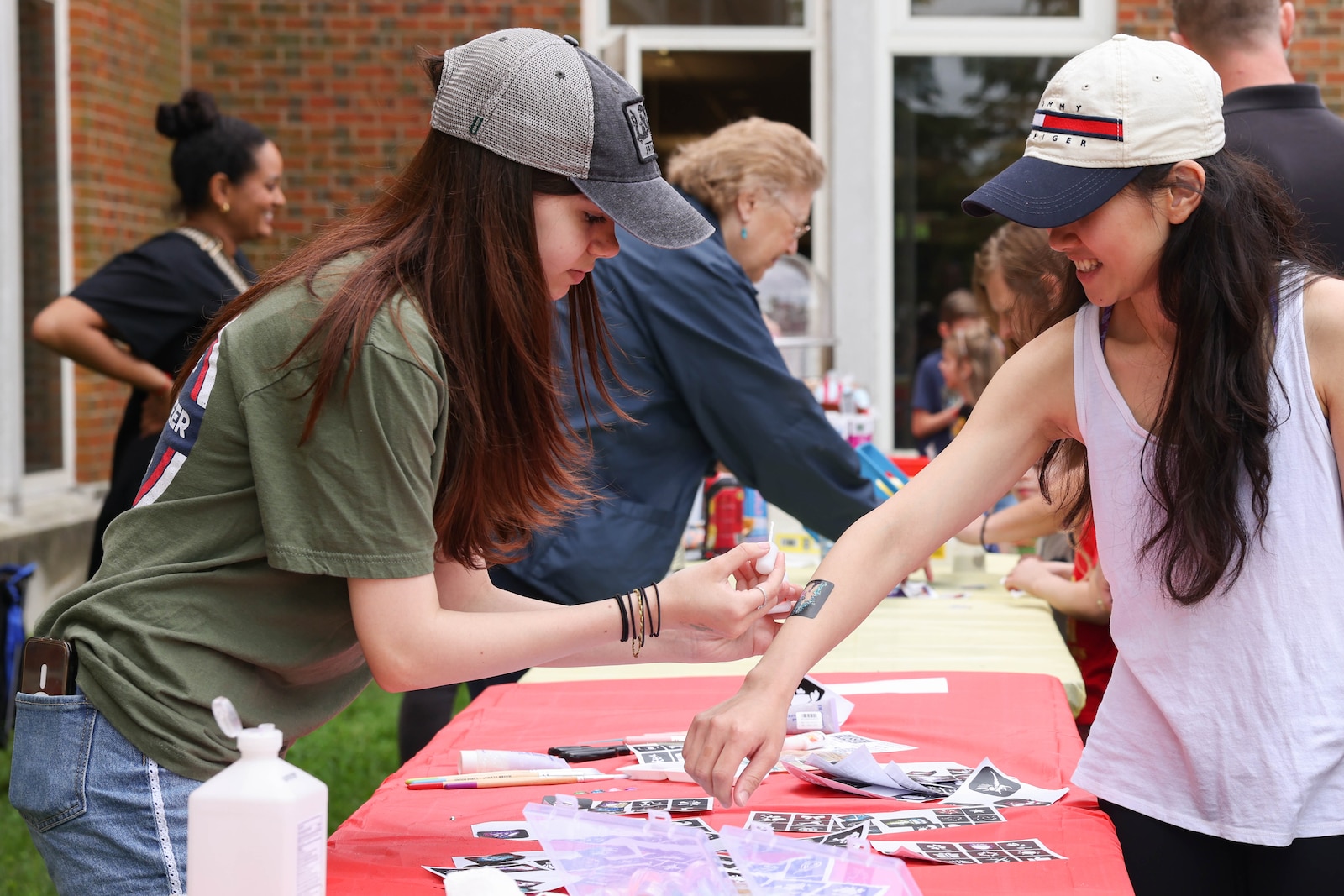 Volunteers apply temporary tattoos to children attending the Library of the Marine Corps Summer Transition event on Marine Corps Base Quantico, Virginia, May 3, 2024. The library hosted the event to showcase the different programs offered across base to support families throughout the summer months. (U.S. Marine Corps photo by Lance Cpl. David Brandes)