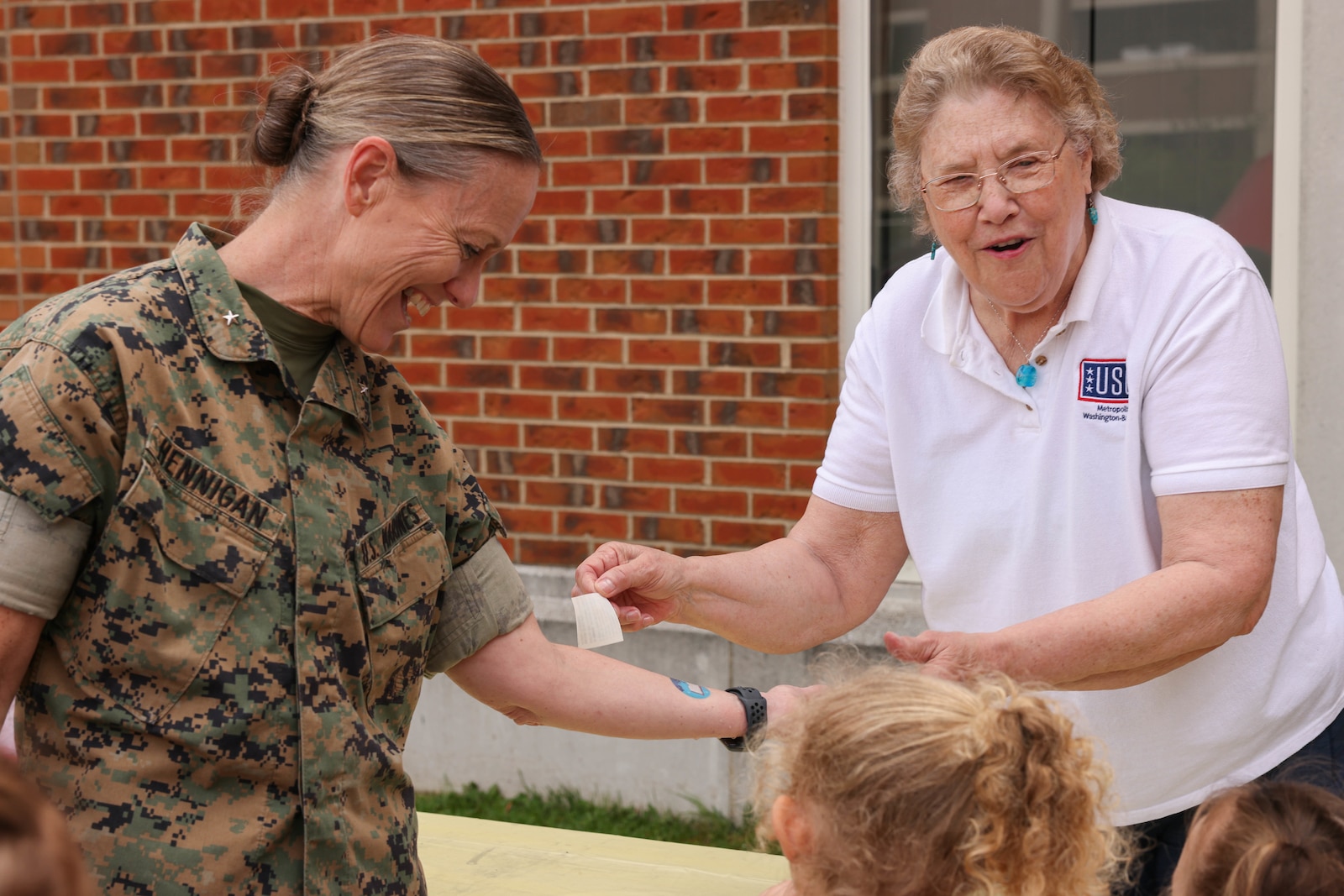 U.S. Marine Corps Brig. Gen. Maura M. Hennigan, the president of Marine Corps University, gets a temporary tattoo during the Library of the Marine Corps Summer Transition event on Marine Corps Base Quantico, Virginia, May 3, 2024. The library hosted the event to showcase the different programs offered across base to support families throughout the summer months. (U.S. Marine Corps photo by Lance Cpl. David Brandes)
