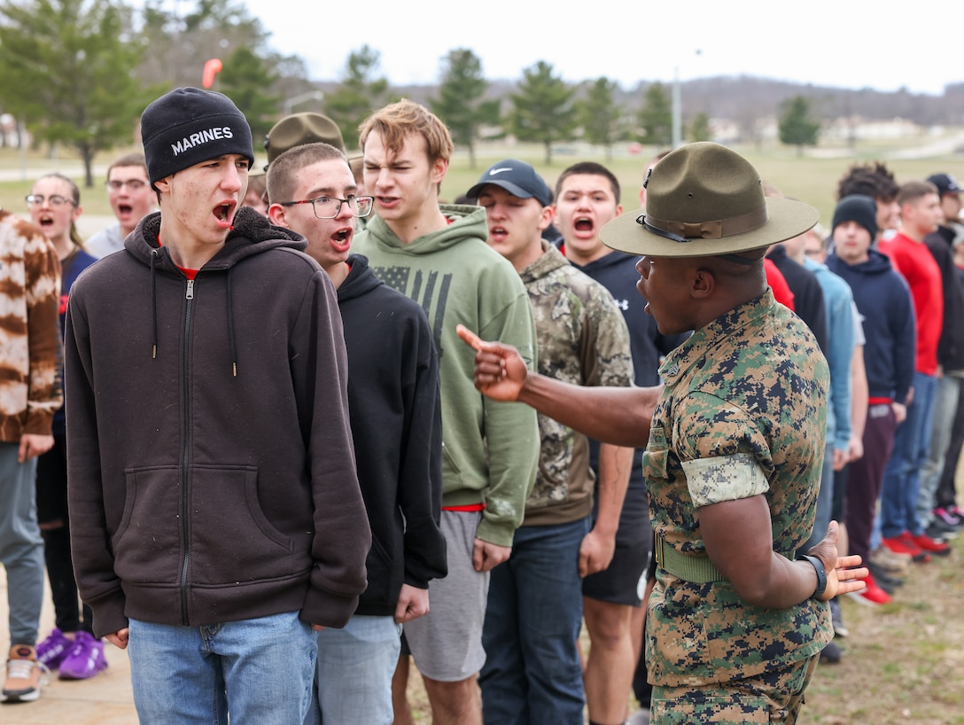 U.S. Marine Corps Sgt. Moses Enrich, right, a Worcester, Massachusetts native and drill instructor, instructs poolees during Recruiting Station Lansing's "mini recruit training" event at Camp Grayling, Grayling, Michigan, April 19, 2024.  The purpose of the event is to further mentally and emotionally prepare poolees for the rigors of recruit training.  (U.S. Marine Corps photo by Sgt. Bernadette Pacheco)