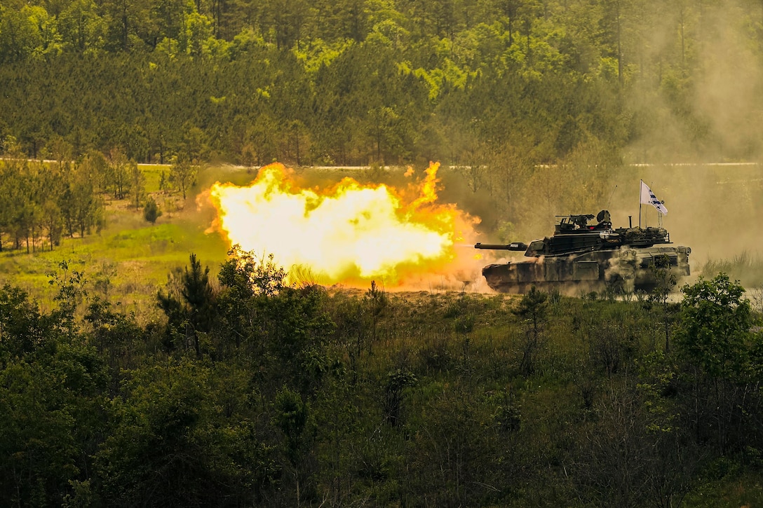 A bright orange flame emits from a military tank during a competition.