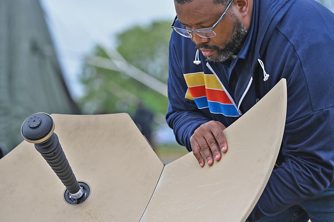 Black man adjusts IT equipment outdoors