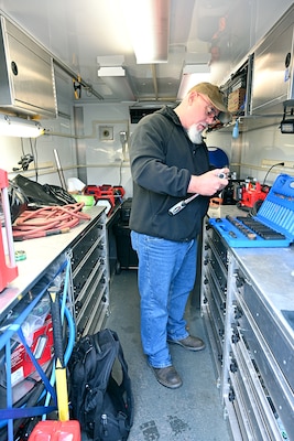 Man stands at a counter with what looks to be tools