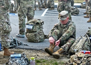 Master Sgt. Kenneth Boff of Joint Force Headquarters, New Hampshire Army National Guard, laces up before the 18.6-mile Norwegian Foot March May 4, 2024, in Concord, N.H. Boff was one of 39 of 61 competitors to complete the event in the prescribed time, finishing in about 4:24:00 while pushing through cramps, blisters and dehydration.