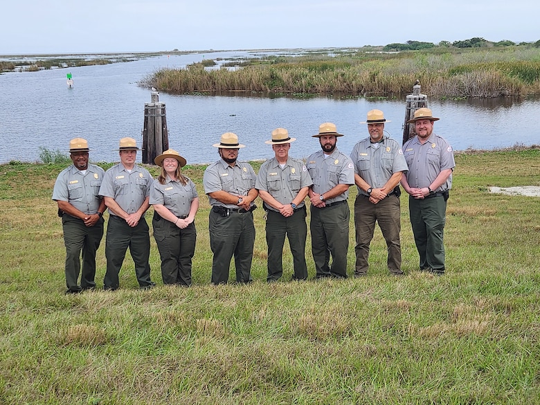 8 park rangers stand on the bank of Lake Okeechobee