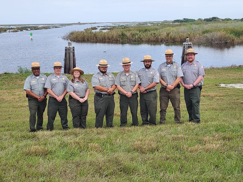 8 park rangers stand on the bank of Lake Okeechobee