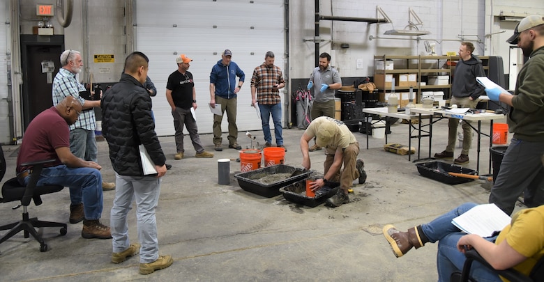 Ken McInally, geotechnical engineer, participates in the practical portion of the ACI exam as other Alaska District teammates look on.