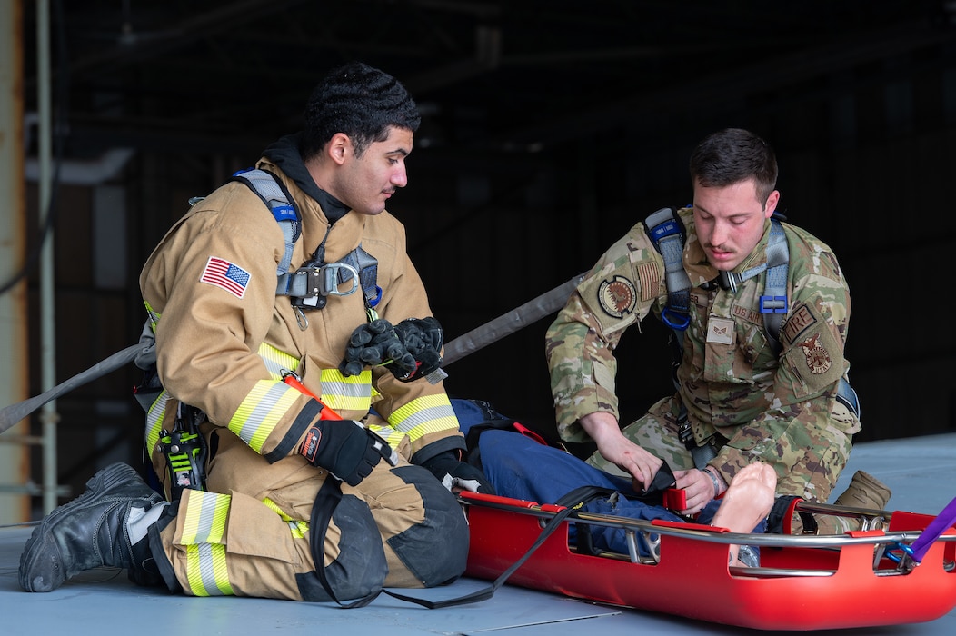 U.S. Air Force Airman 1st Class Brian Castro, left, 436th Civil Engineer Squadron fire department firefighter, and Senior Airman Matthew Maier, right, 436th CES fire department driver operator, secure a mannequin in a Stokes basket during a simulated rescue at Dover Air Force Base, Delaware, May 3, 2024. Dover AFB first responders and the Dover Fire Department participated in a joint rescue exercise in an annual confined-space extraction exercise of a mannequin overcome by simulated fuel vapors on top of the left wing of a C-5M Super Galaxy. (U.S. Air Force photo by Roland Balik)