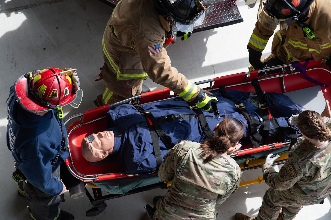 A mannequin used in a simulated rescue is tended to by first responders after being lowered to the ground at Dover Air Force Base, Delaware, May 3, 2024. Dover AFB first responders and the Dover Fire Department participated in an annual confined-space extraction exercise of a mannequin overcome by simulated fuel vapors on top of the wing of a C-5M Super Galaxy. (U.S. Air Force photo by Roland Balik)