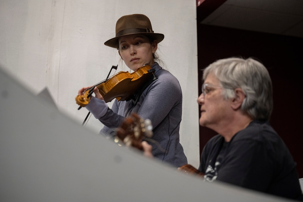 A women plays the violin wearing a brown hat.