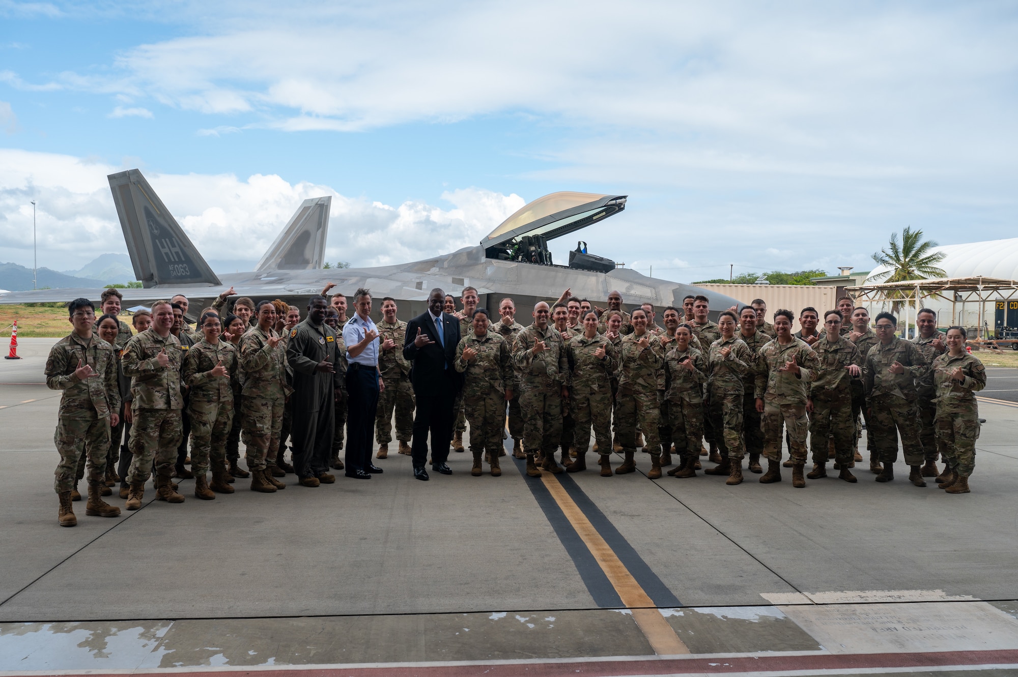 Secretary of Defense stands with a group of Airmen during a group photo.