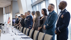 People in formal military dress standing before a table