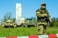 A Danish volunteer assigned to the Bornholm Home Guard stands guard while U.S. Navy Sailors rehearse the deployment of a containerized missile system on Bornholm, Denmark, May 7, 2024.