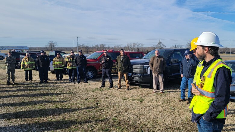 A half circle of 10 people standing in a field.