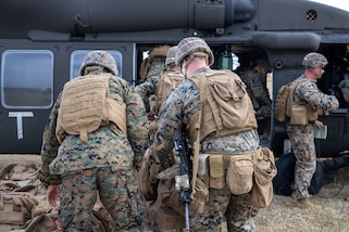 U.S. Marines load gear onto a military helicopter.