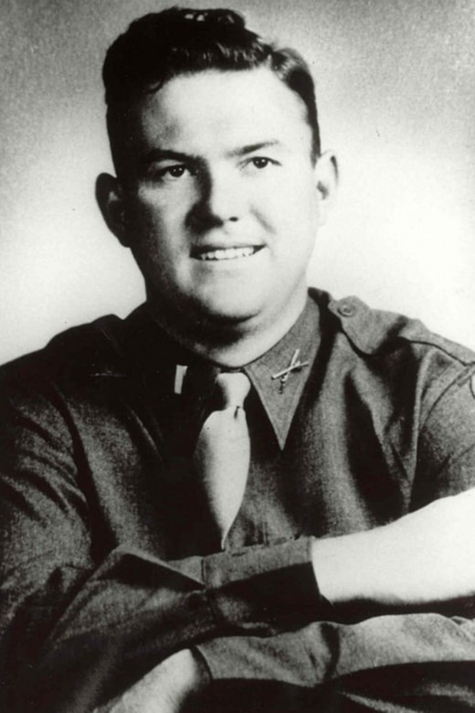 A smiling service member in uniform poses for a photo with their arms crossed.