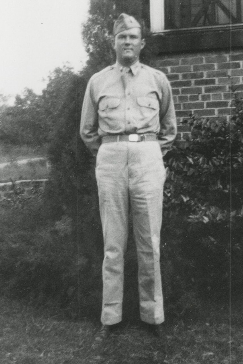A person in uniform poses for a photo with their hands behind their back.