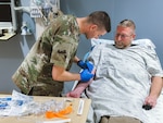 Staff Sgt. Dustin Allison, an aerospace medic with the 157th Medical Group, draws blood from Kevin Drew, Catholic Medical Center Emergency Room director, as part of a training affiliation agreement between the New Hampshire Air National Guard and CMC April 17, 2024, in Manchester, New Hampshire. The partnership provides an extra set of hands in the hospital’s emergency department and gives the Airmen real-world training with industry partners on more than 100 critical skill-based responsibilities.