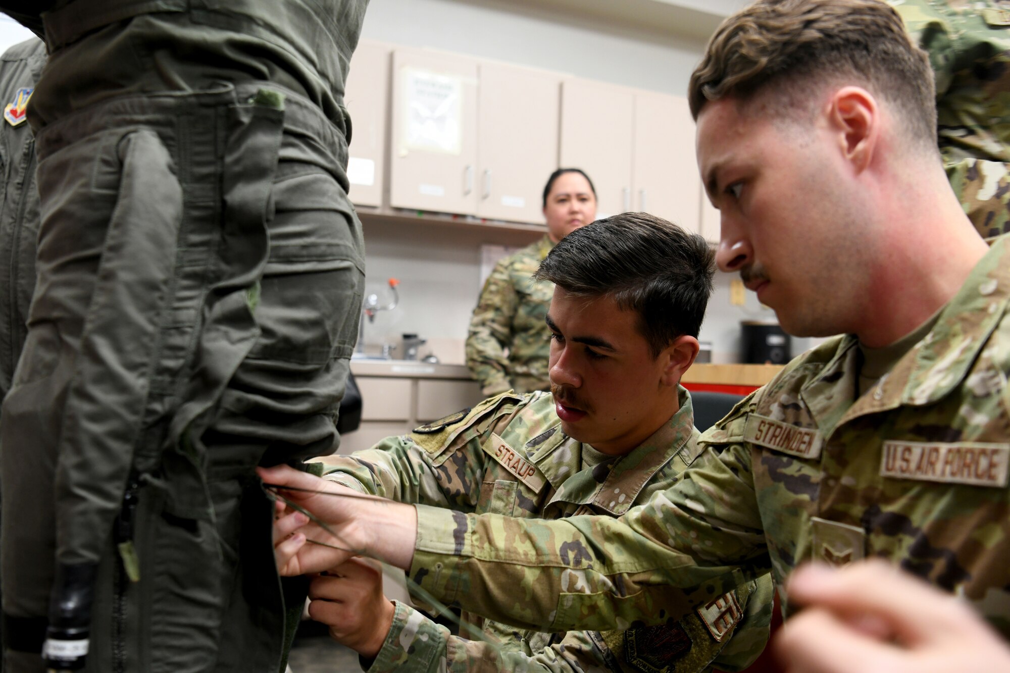 U.S. Air Force Senior Airman Kyle Straup, center, and Airman 1st Class Chase Strinden, right, 20th Operations Support Squadron Aircrew Flight Equipment technicians, lace up the legs of an anti-g suit worn by NASCAR driver Joey Logano at Shaw Air Force Base, S.C., May 7, 2024. Shaw AFB is an assignment of choice for both enlisted and officers, offering a support and opportunity-rich environment for Airmen to develop and thrive, both personally and professionally, while working to support the mission. (U.S. Air Force photo by Staff Sgt. Kelsey Owen)