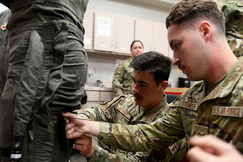 U.S. Air Force Senior Airman Kyle Straup, center, and Airman 1st Class Chase Strinden, right, 20th Operations Support Squadron Aircrew Flight Equipment technicians, lace up the legs of an anti-g suit worn by NASCAR driver Joey Logano at Shaw Air Force Base, S.C., May 7, 2024. Shaw AFB is an assignment of choice for both enlisted and officers, offering a support and opportunity-rich environment for Airmen to develop and thrive, both personally and professionally, while working to support the mission. (U.S. Air Force photo by Staff Sgt. Kelsey Owen)