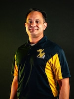 Man standing in front of polo standing in front of dark background.