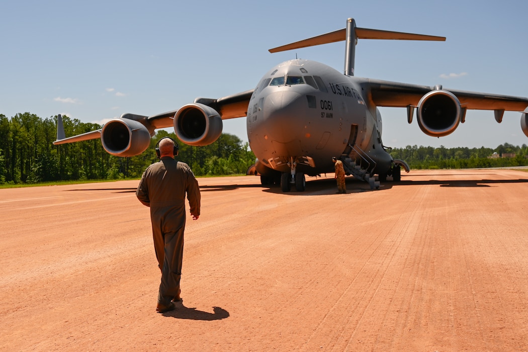 U.S. Air Force Lt. Col. Andrew J. Stewart, 97th Operations Group deputy commander, walks toward a C-17 Globemaster III aircraft at Fort Johnson, Louisiana, April 30, 2024. Stewart participated in a large force exercise that challenged the pilots’ capabilities to operate the aircraft in an austere environment. (U.S. Air Force photo by Airman 1st Class Jonah G. Bliss)
