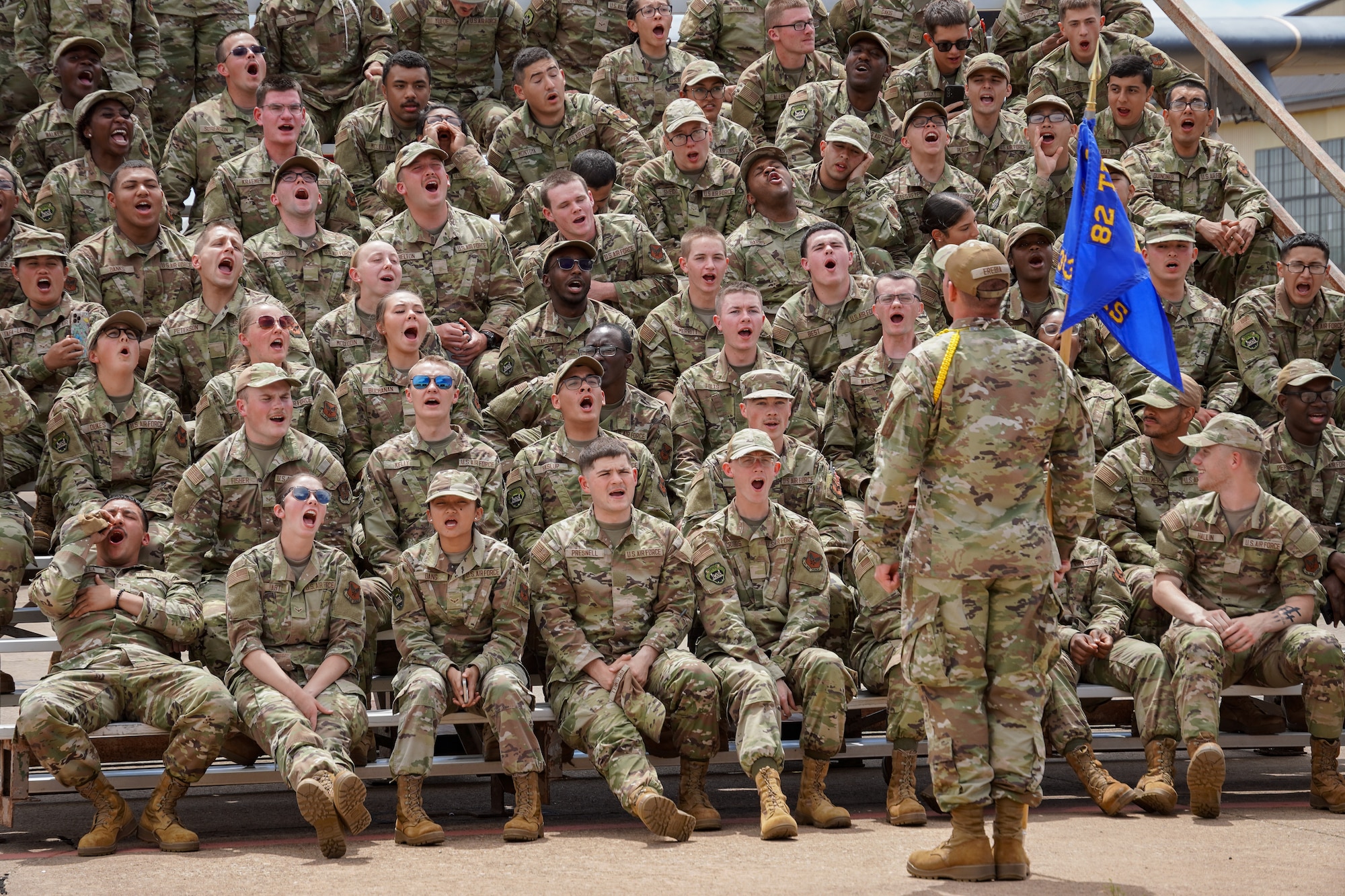 Airmen sit in a crowd on bleachers
