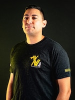 Man wearing a polo standing in front of a black background.