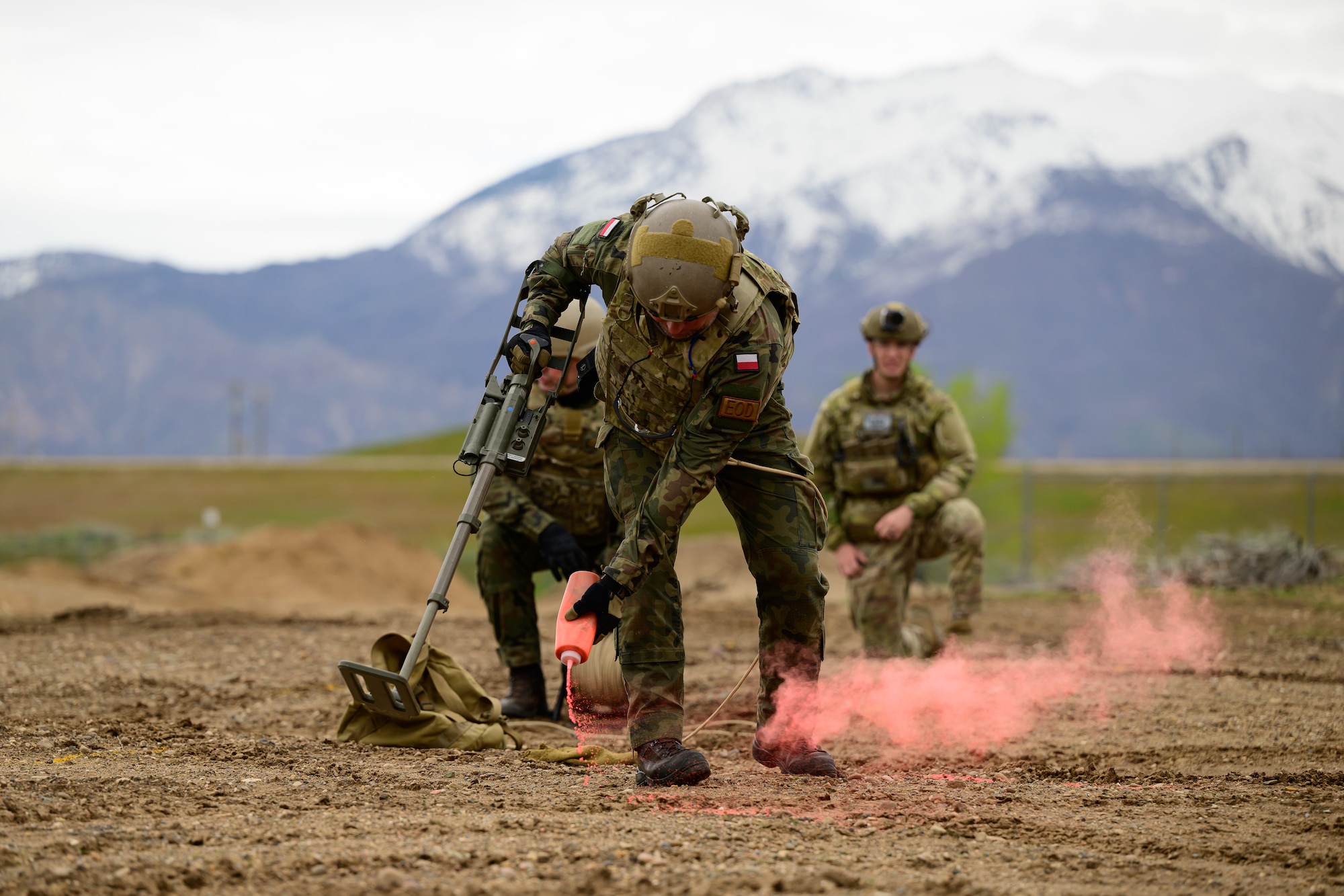 A military members uses pink smoke to mark a target