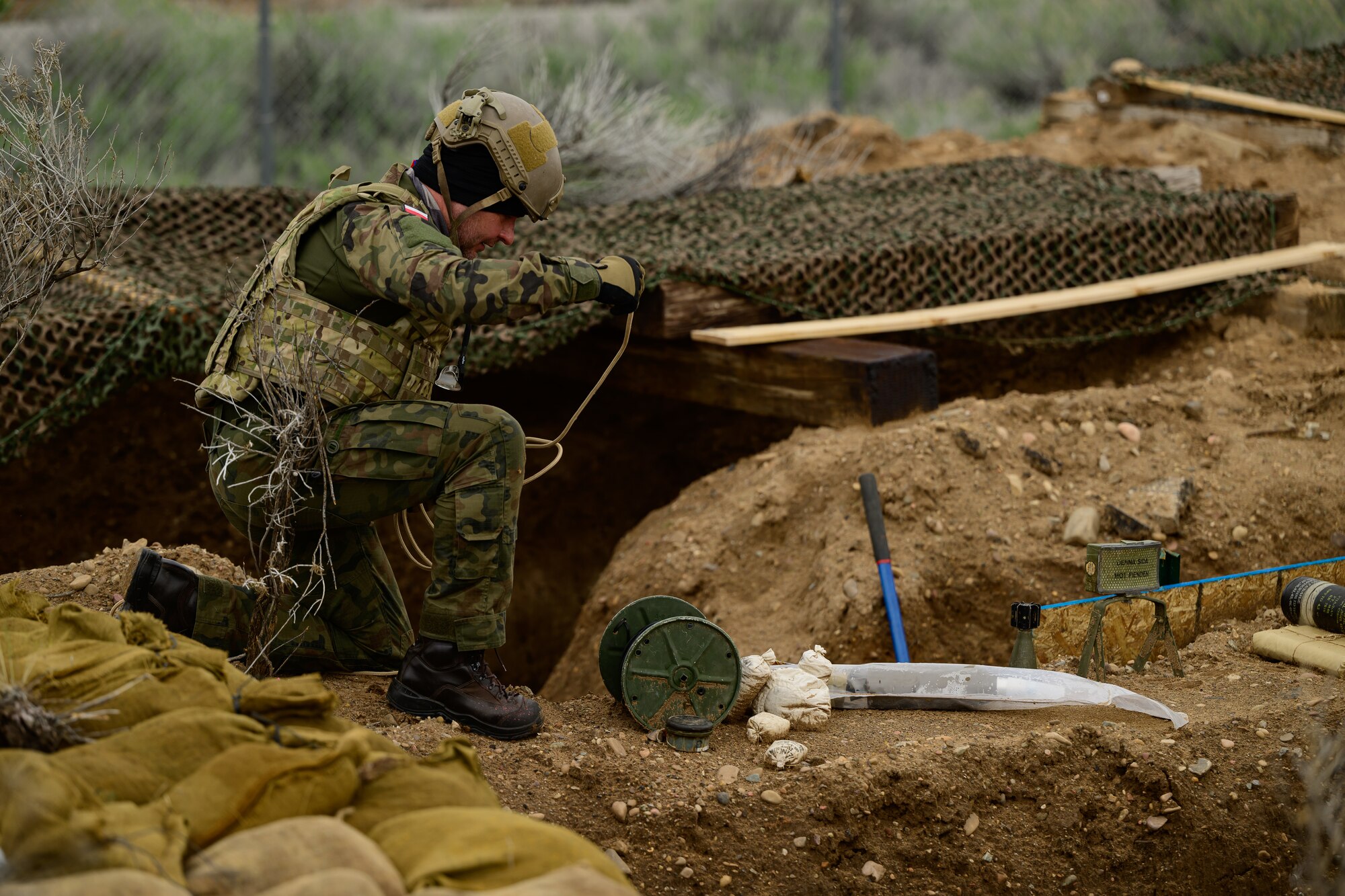 A military member works above a trench