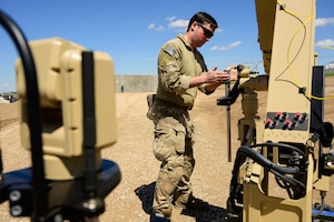 An airman works with a piece of equipment in a desert surrounding