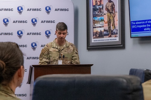 Airmen standing at a podium talking and presenting