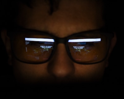 A person wearing glasses looks at a computer screen.