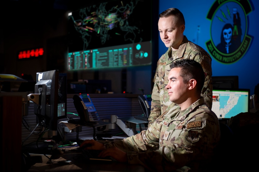 Two service members work at a computer terminal.