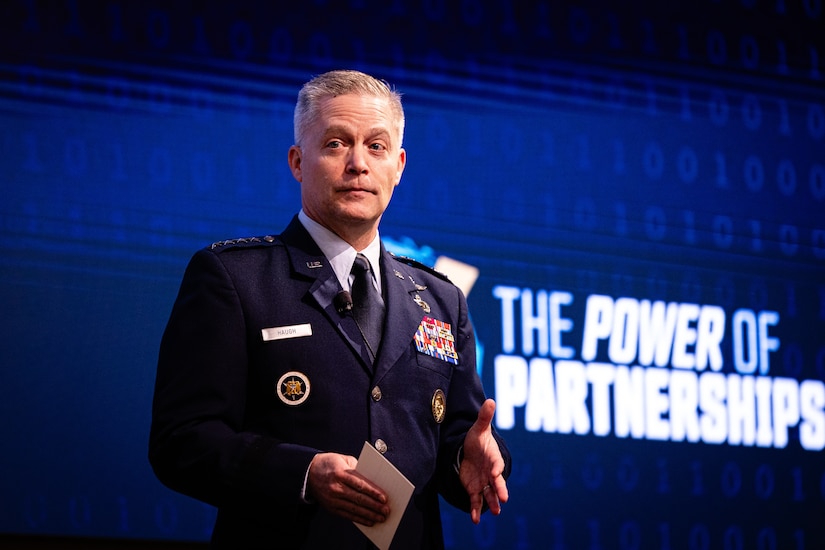 An Air Force officer in uniform gestures with his hands while on stage.