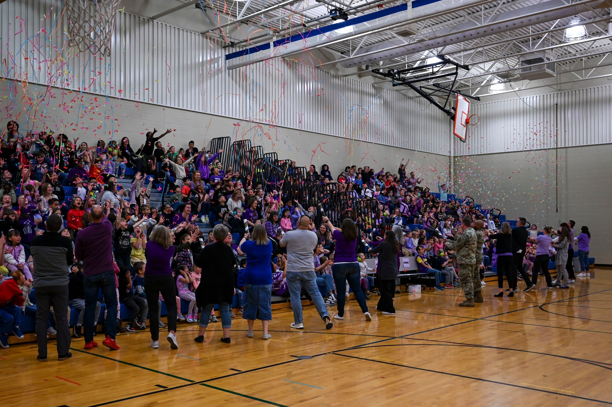 Teachers shoot confetti on an audience of students.