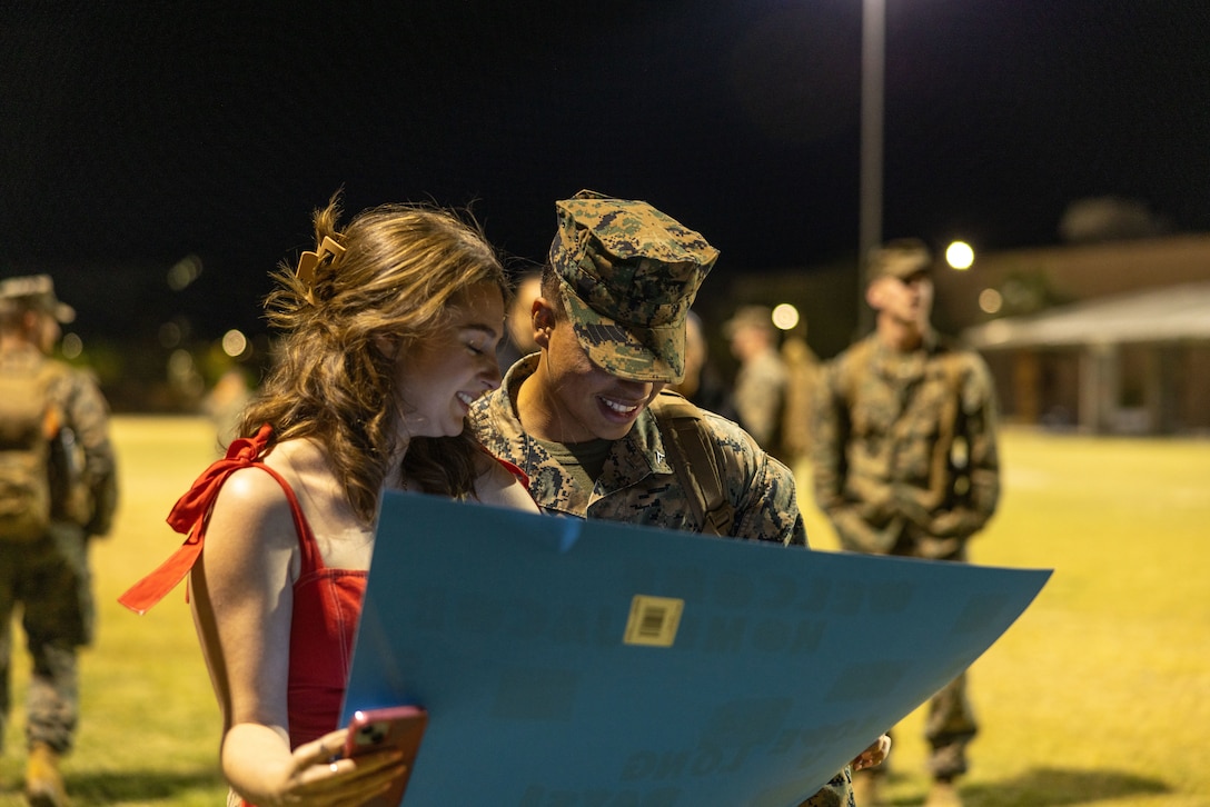 A U.S. Marine with 2nd Battalion, 7th Marine Regiment, 1st Marine Division, reads a sign during his return from a Unit Deployment Program at Victory Field, Marine Corps Air-Ground Combat Center, Twentynine Palms, April 17, 2024. UDP’S enhance the United States forward presence and provides a consistent and rapid response capability. (U.S. Marine Corps photo by Lance Cpl. Anna Higman)