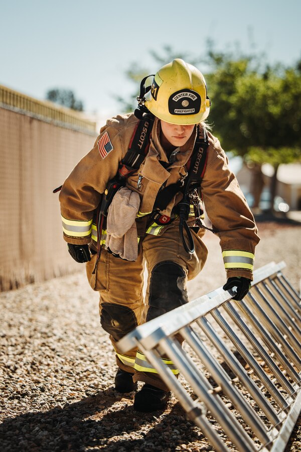 Paige Kelly, a Hemet, California native, firefighter with The Combat Center Fire Department, Marine Corps Air-Ground Combat Center, moves a ladder before routine training at MCAGCC, Twentynine Palms, California, April 22, 2024. The Combat Center Fire Department’s mission is to improve the quality of life at the MCAGCC by providing high quality emergency fire and rescue services, and a fire prevention program.  (U.S. Marine Corps photo by Lance Cpl. Richard PerezGarcia)