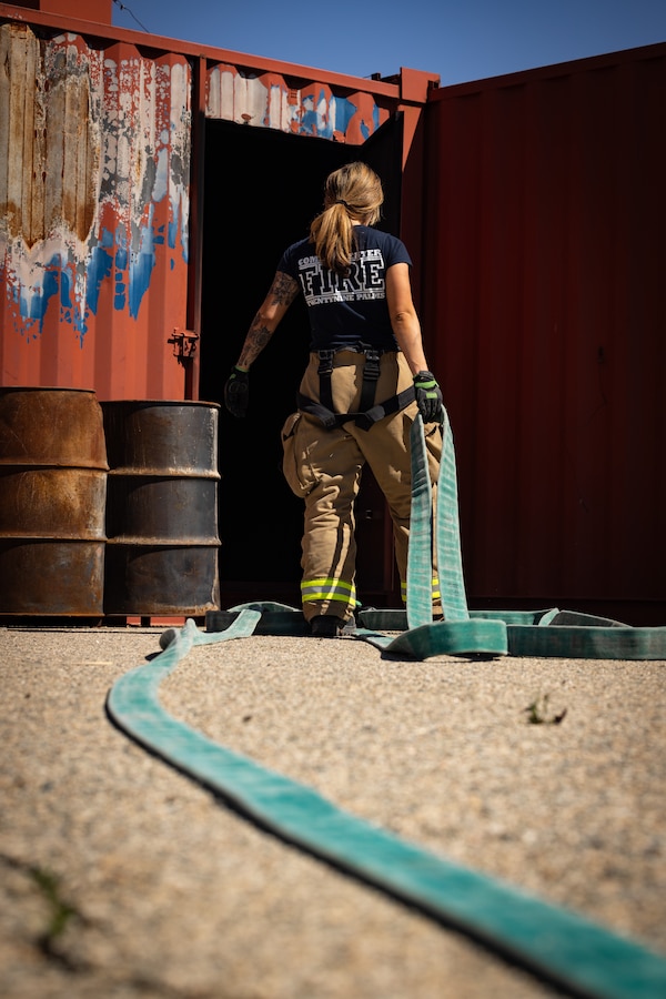 Paige Kelly, a Hemet, California native, firefighter with The Combat Center Fire Department, Marine Corps Air-Ground Combat Center, prepares a fire hose for routine training at MCAGCC, Twentynine Palms, California, April 22, 2024. The Combat Center Fire Department’s mission is to improve the quality of life at the MCAGCC by providing high quality emergency fire and rescue services, and a fire prevention program.  (U.S. Marine Corps photo by Cpl. Hunter Wagner)