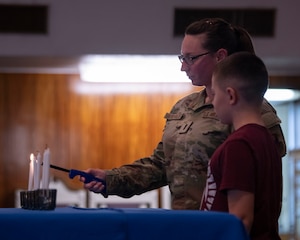A military woman and her son light a candle.