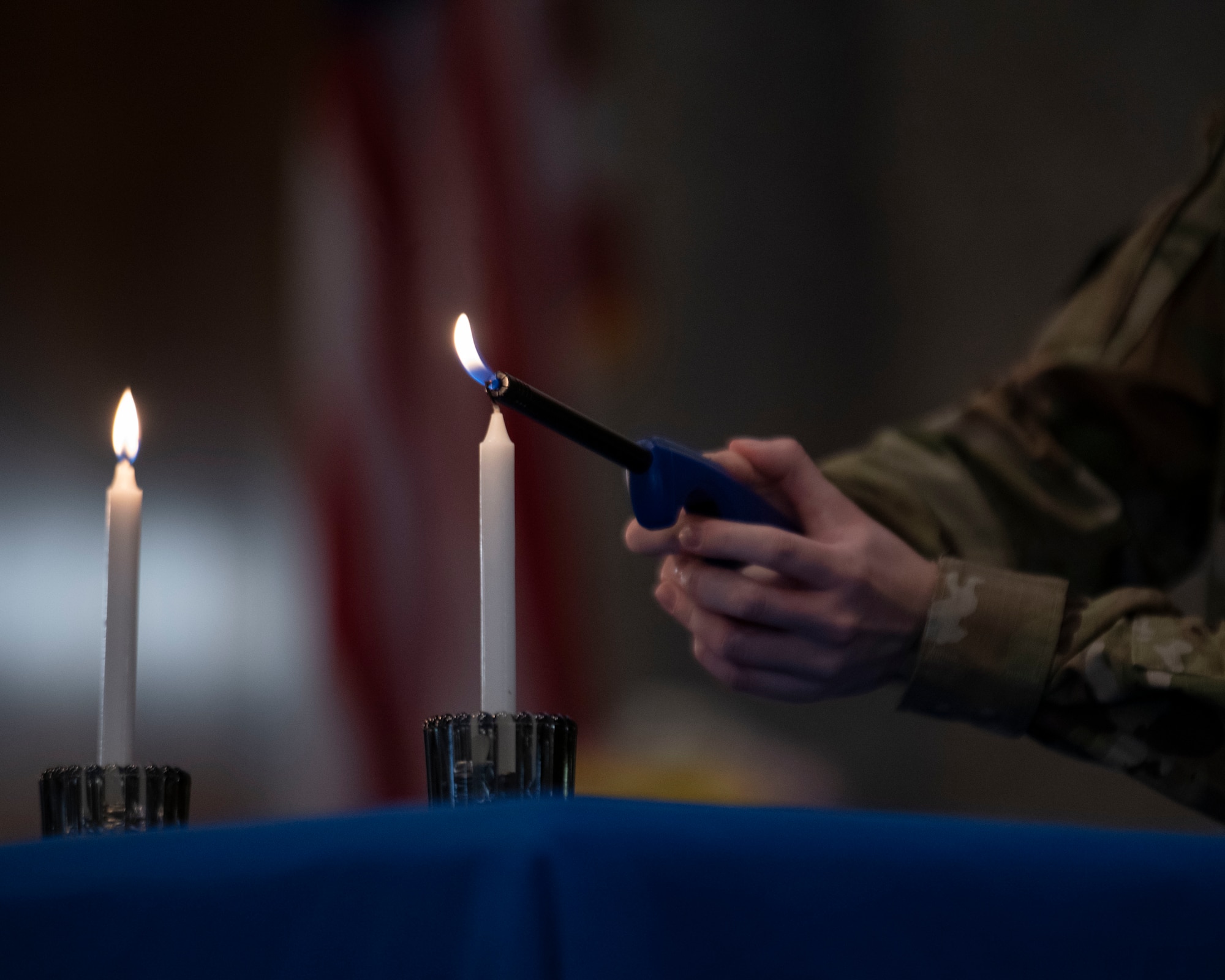 A military member lights a candle.