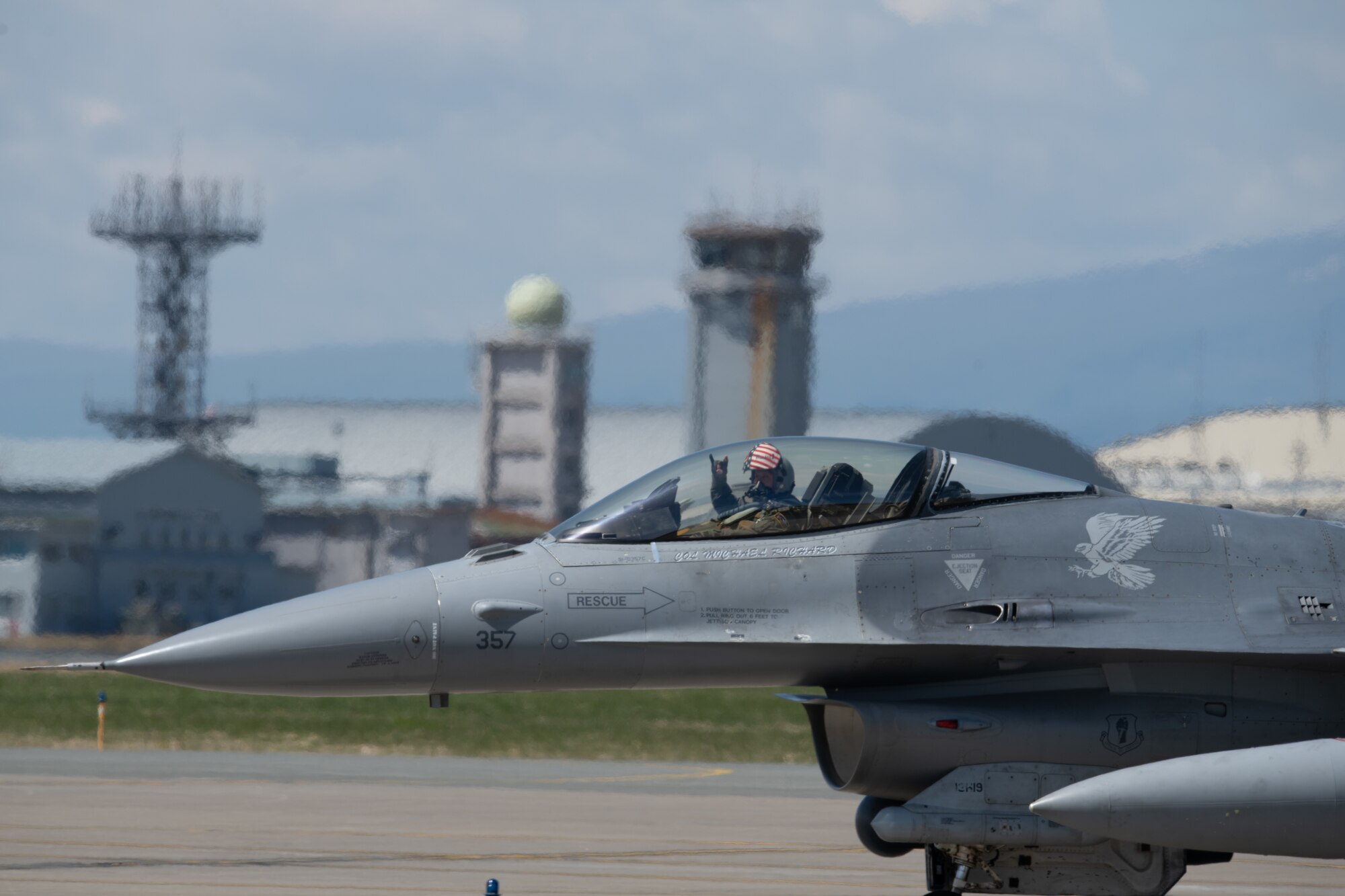 An F-16 fighter pilot in his cockpit waves to the camera