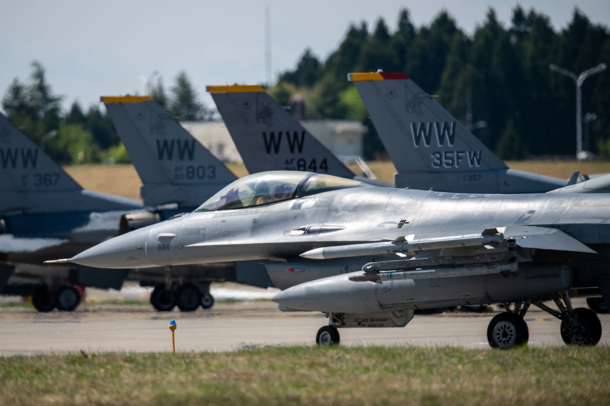 F-16 fighter jet taxis behind other F-16s on the flightline