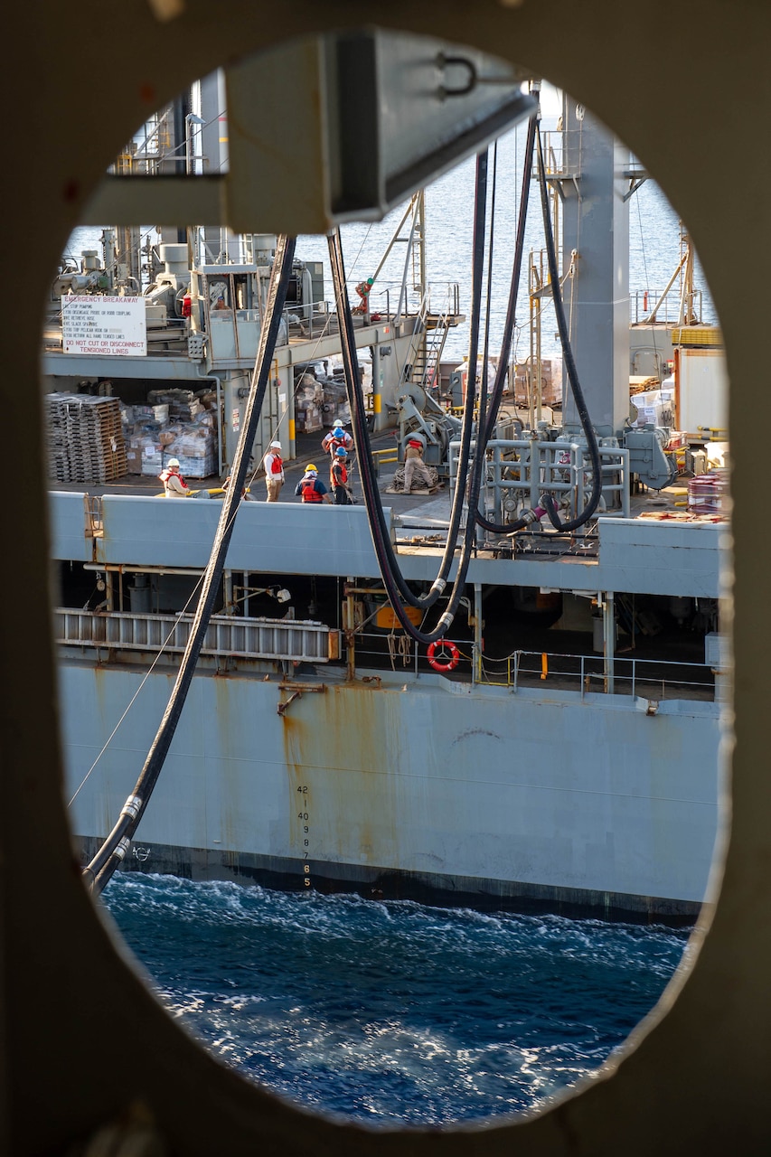 A wire connects to a ship as seen through the window of the a ship.