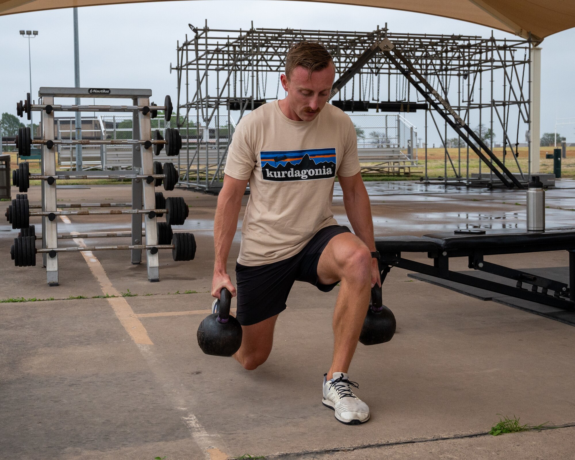 A U.S. Air Force Airman carries weights while lunging at the outdoor Losano Fitness Center at Laughlin Air Force Base, Texas, April 25, 2024. The Losano Fitness Center has outdoor and indoor facilities available to Airmen, no matter the time of day or weather. (U.S. Air Force photo by Staff Sgt. Nicholas Larsen)