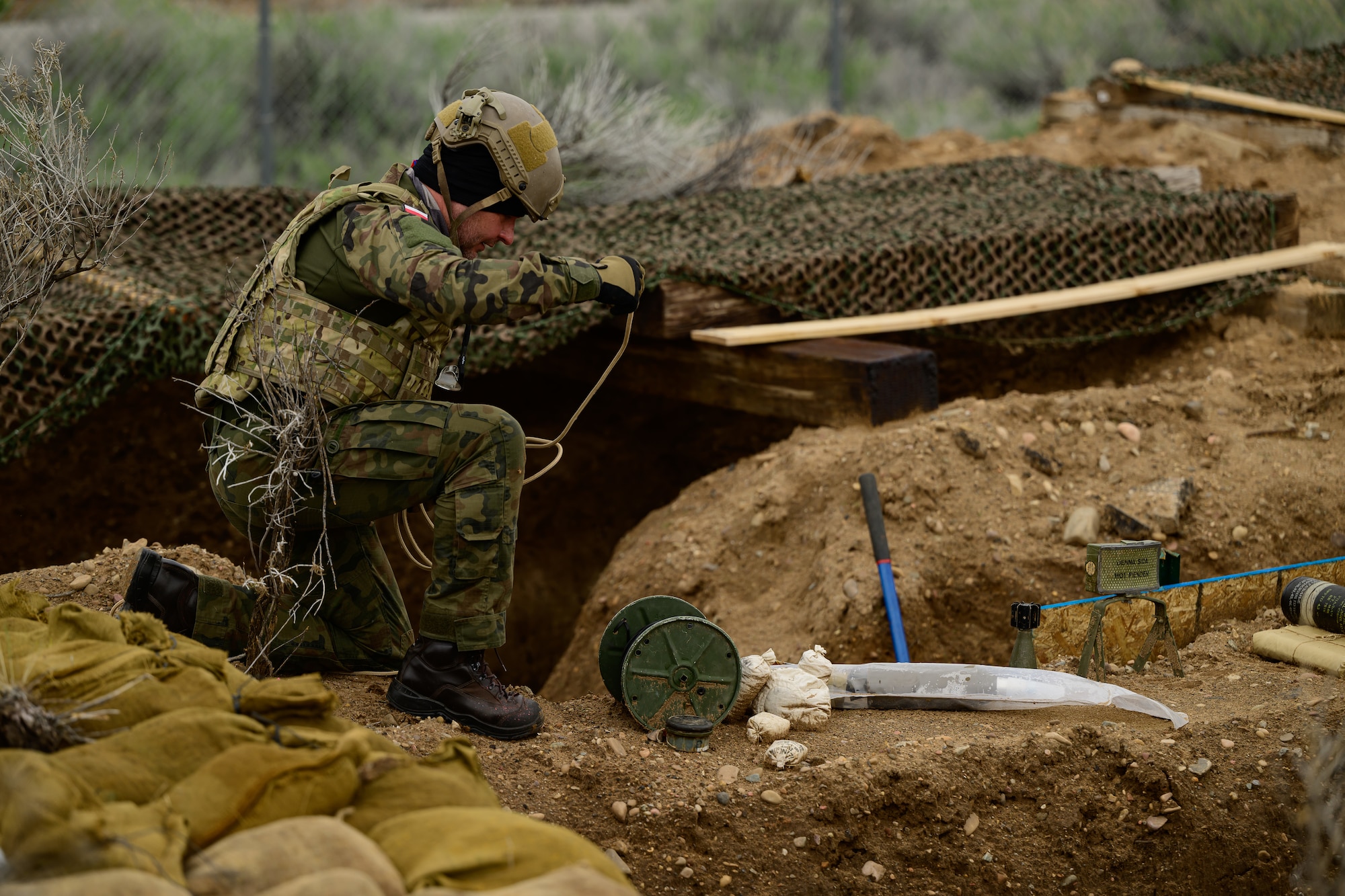 A military member works above a trench