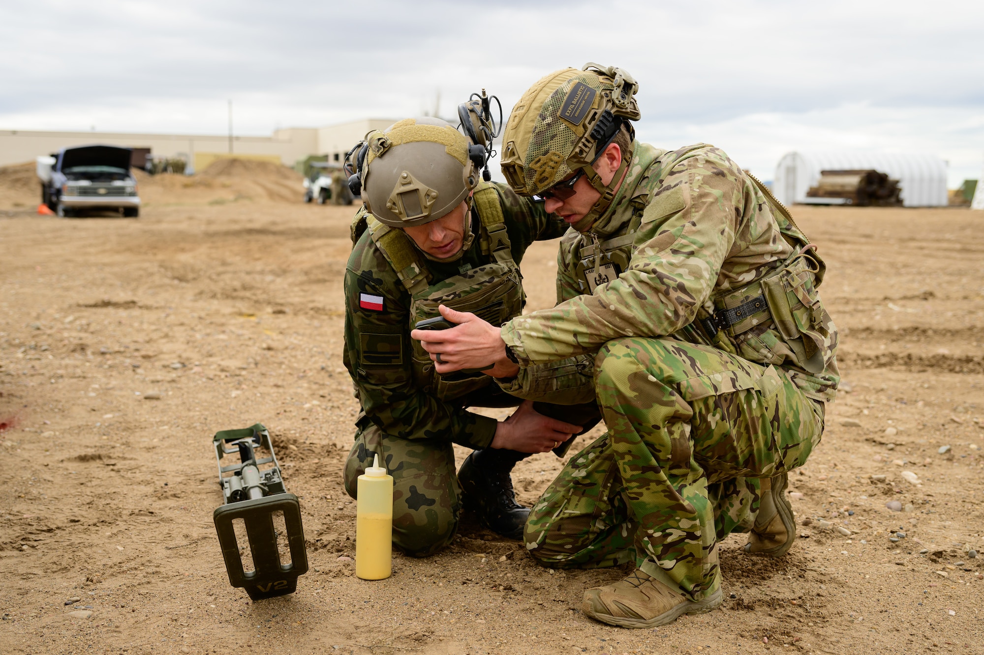 Two men look a piece of equipment while planning to use yellow marker smoke